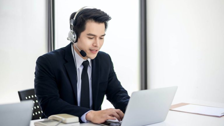 Asian man wearing headphones working as a call center in an office.